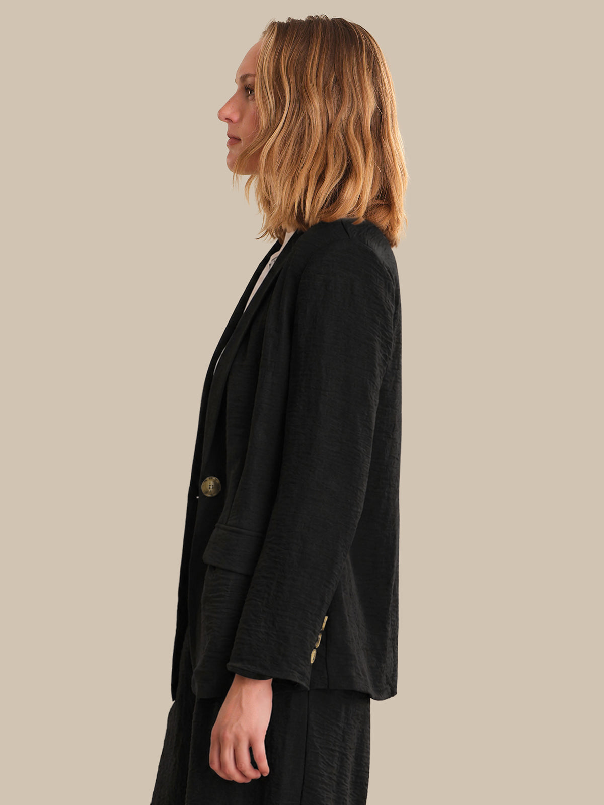 Person wearing a black blazer on a beige background