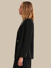 Person wearing a black blazer on a beige background