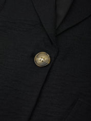 Close-up of a black blazer with a gold button
