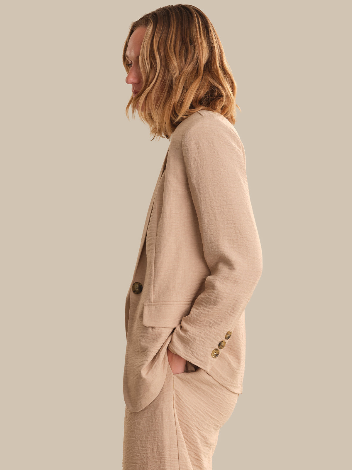 Woman wearing a beige blazer against a plain background