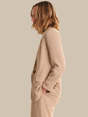 Woman wearing a beige blazer against a plain background