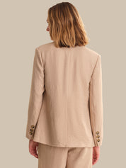 Person wearing a beige suit on a plain background