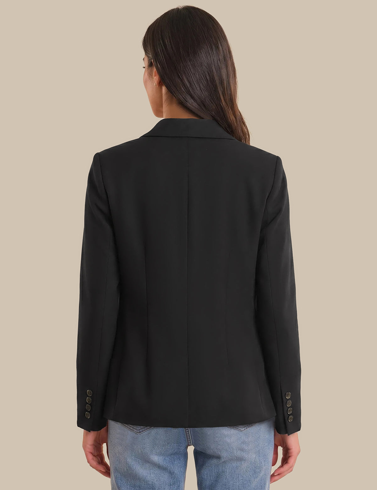Person wearing a black blazer with a beige background