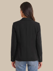 Person wearing a black blazer with a beige background