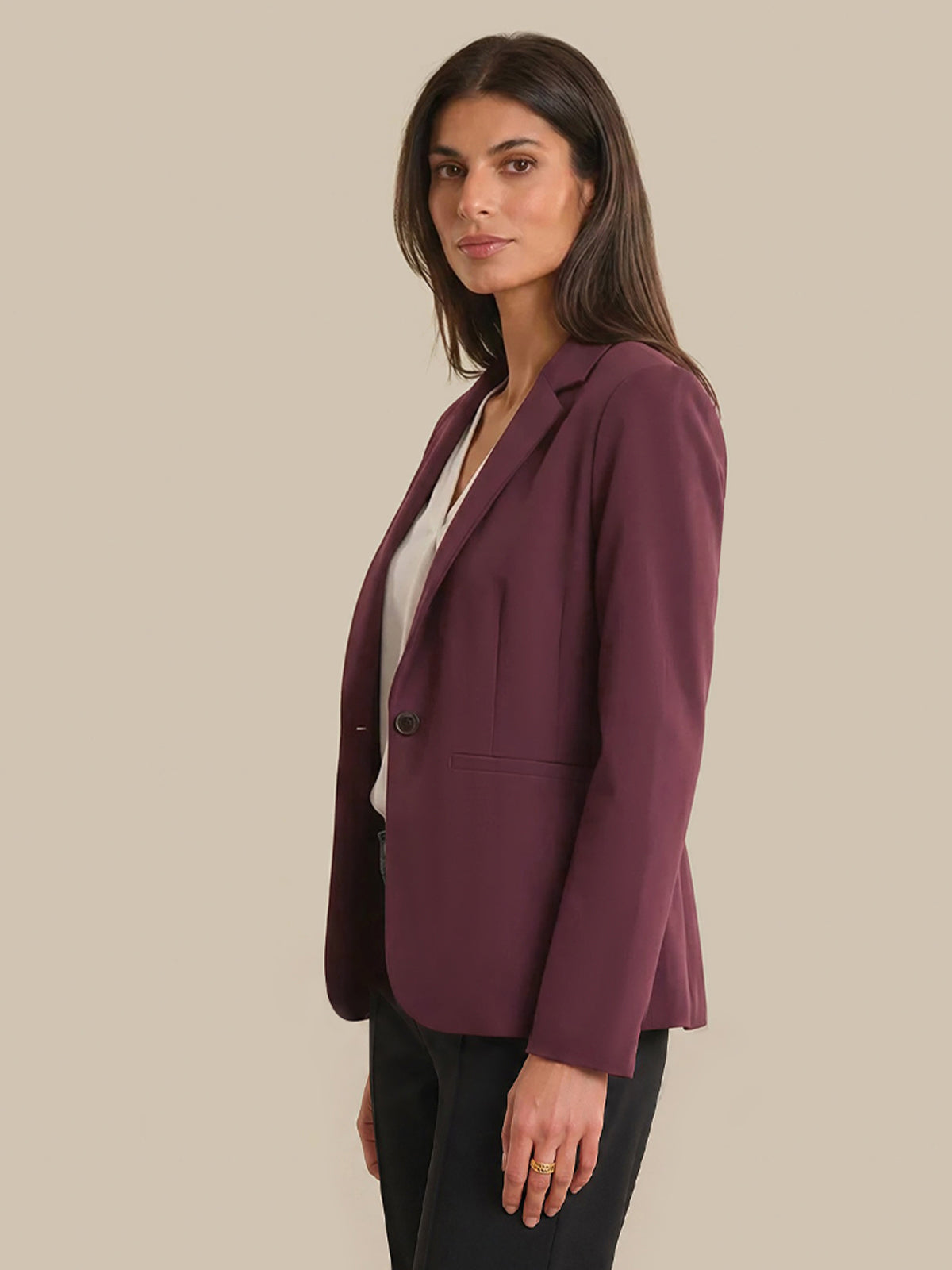 Woman wearing a burgundy blazer on a beige background