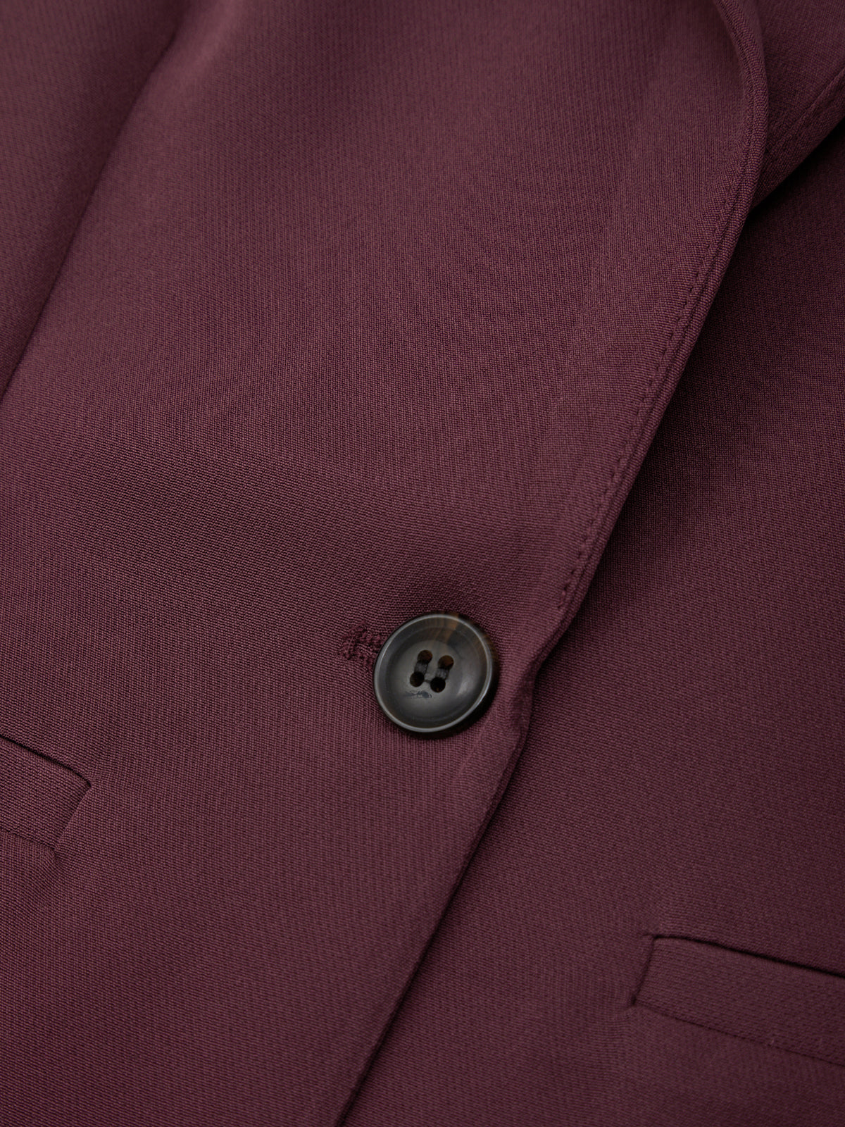 Close-up of a burgundy jacket with a button