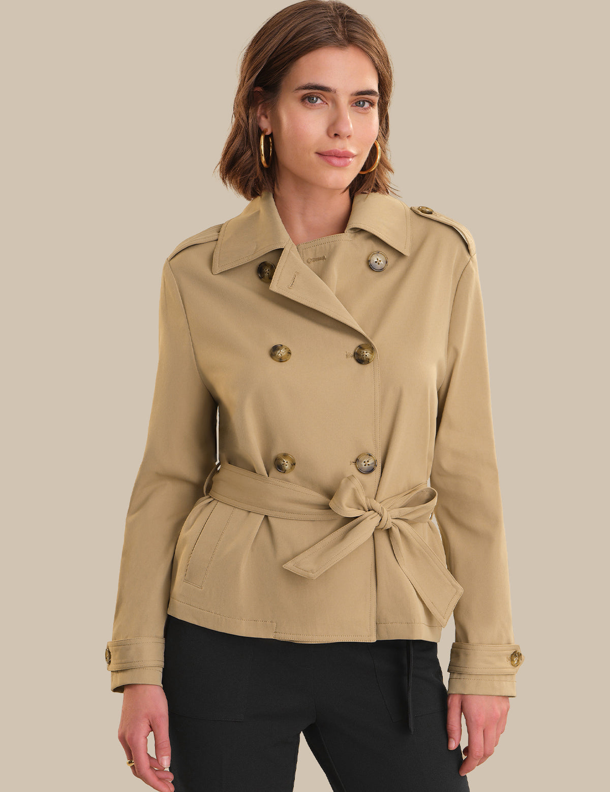 Woman wearing a beige trench coat on a beige background