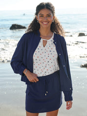 Woman wearing a navy blue outfit with a white top with star pattern on a beach.
