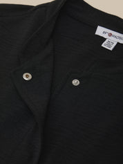 Close-up of a black shirt with button details and a brand label on a beige background