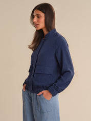 Woman wearing a blue jacket and light blue pants against a beige background