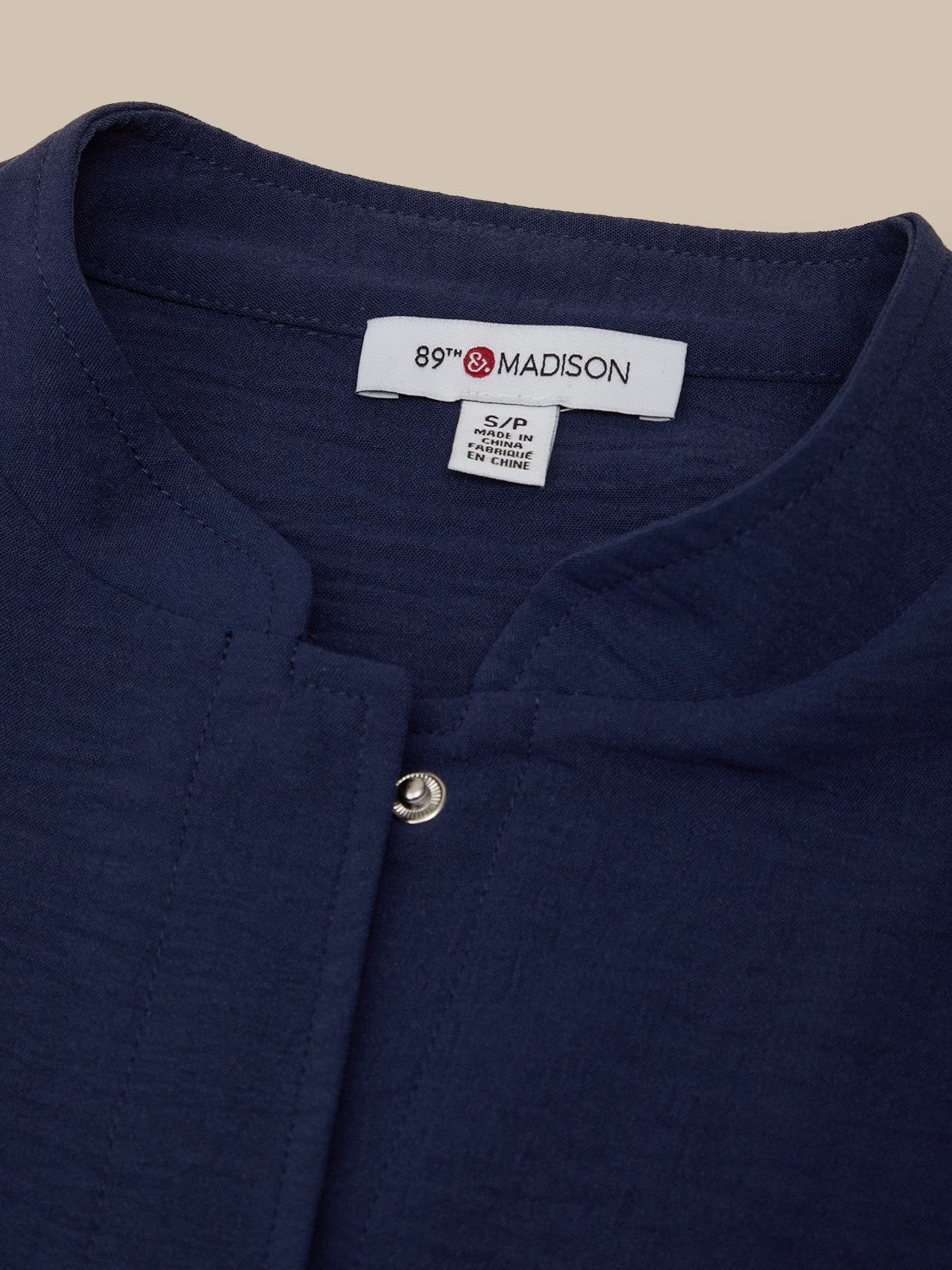 Navy blue shirt with a visible brand label on a beige background