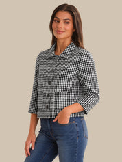 Woman wearing a black and white checkered jacket and blue jeans on a beige background