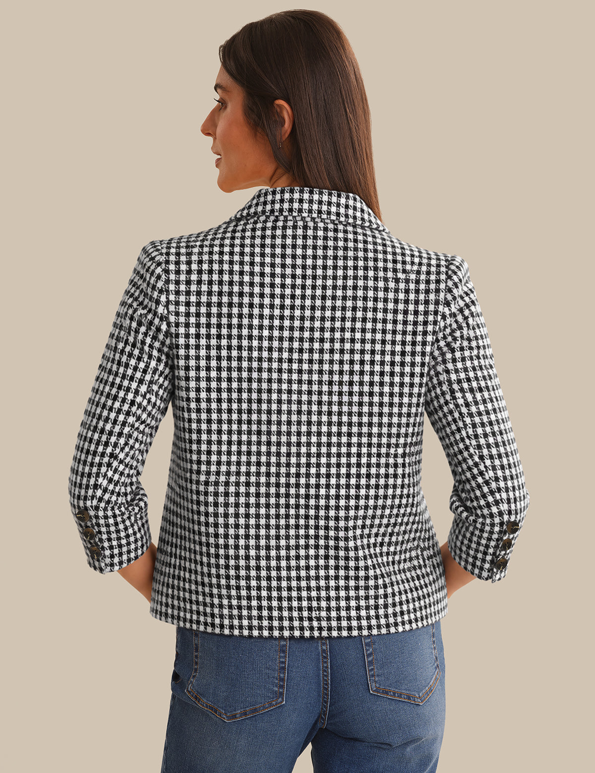 Woman wearing a black and white checkered jacket on a beige background
