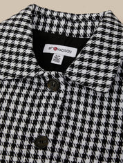 Close-up of a houndstooth patterned coat with a brand label.