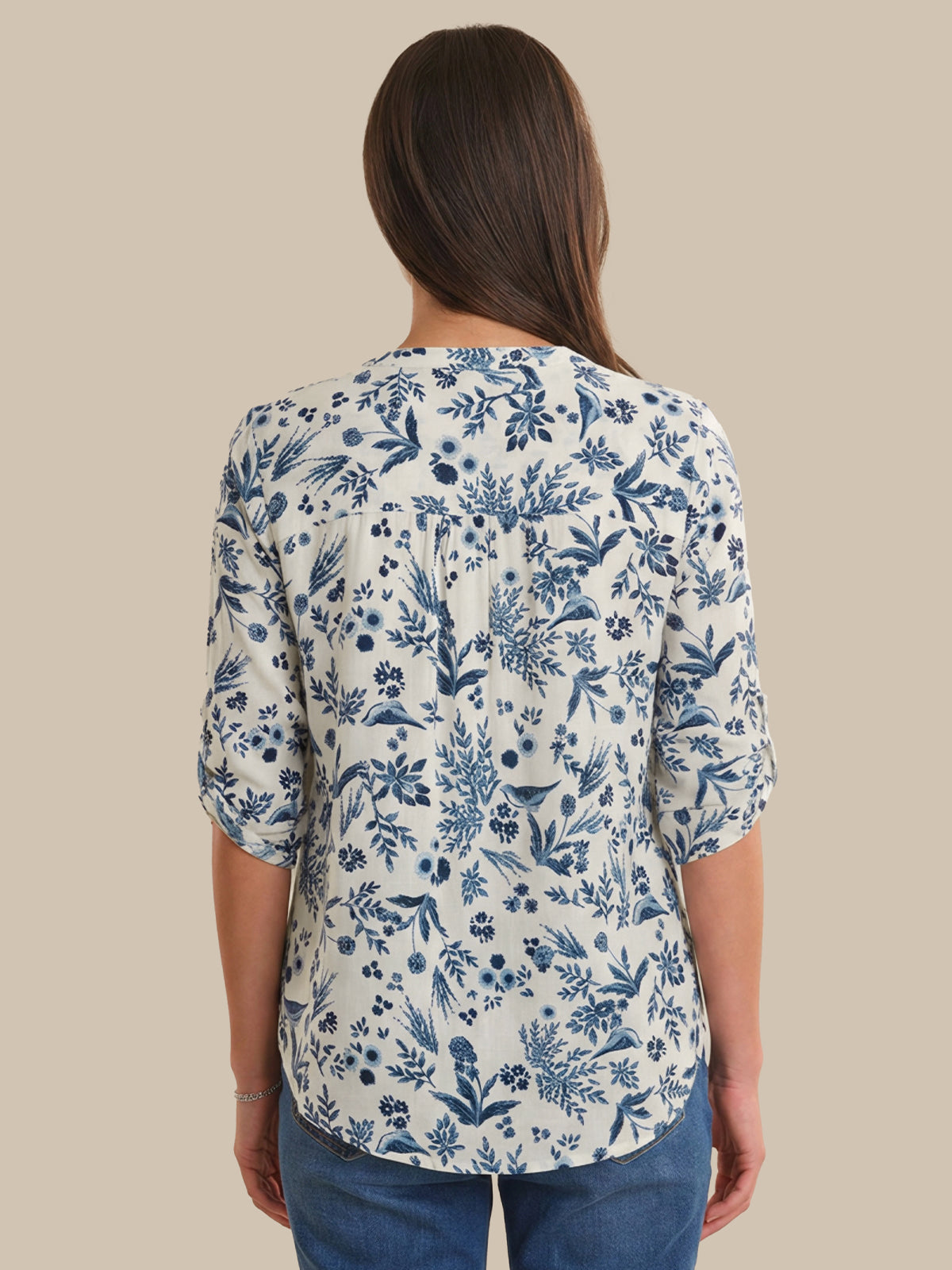 Woman wearing a blue floral patterned shirt on a beige background