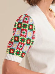 Colorful crochet arm sleeve worn by a person on a beige background