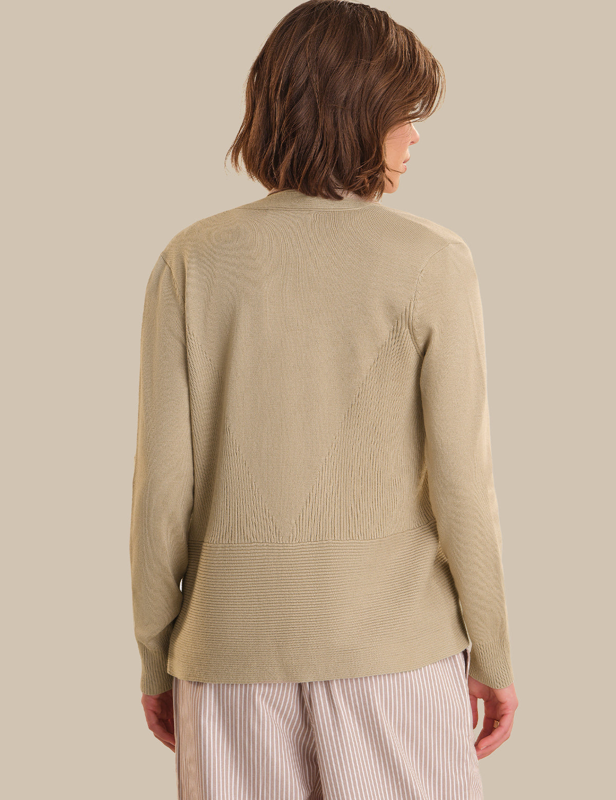 Person wearing a beige sweater against a plain background