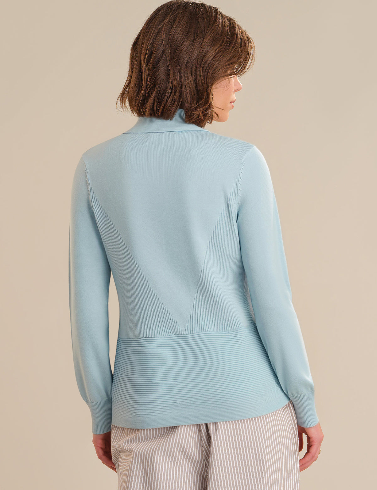 Person wearing a light blue sweater against a beige background