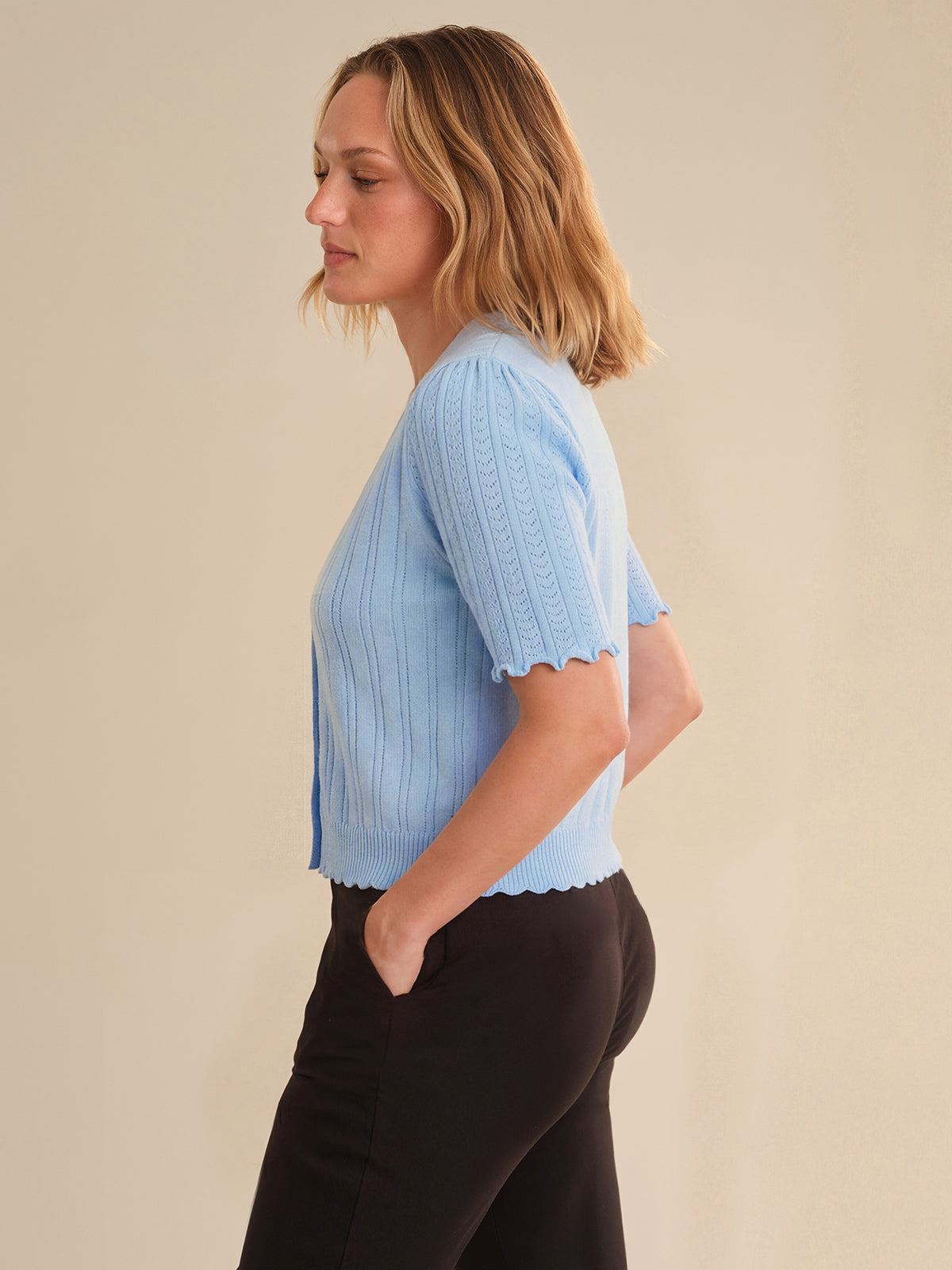 Woman wearing a light blue ribbed sweater against a beige background