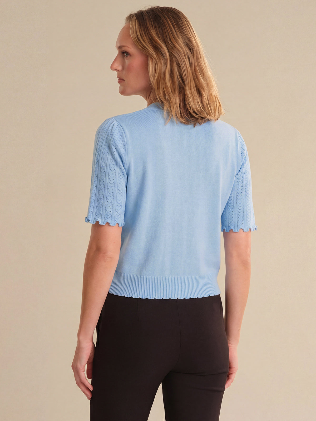 Woman wearing a light blue knitted top against a beige background