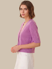 Woman wearing a purple textured cardigan against a beige background