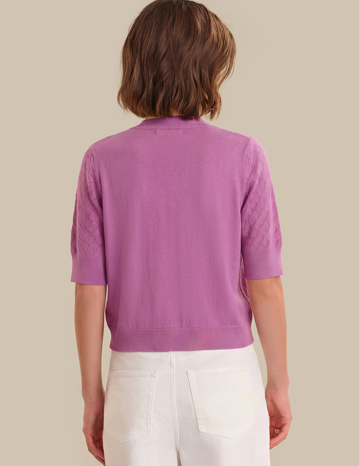 Person wearing a purple cardigan with a neutral background
