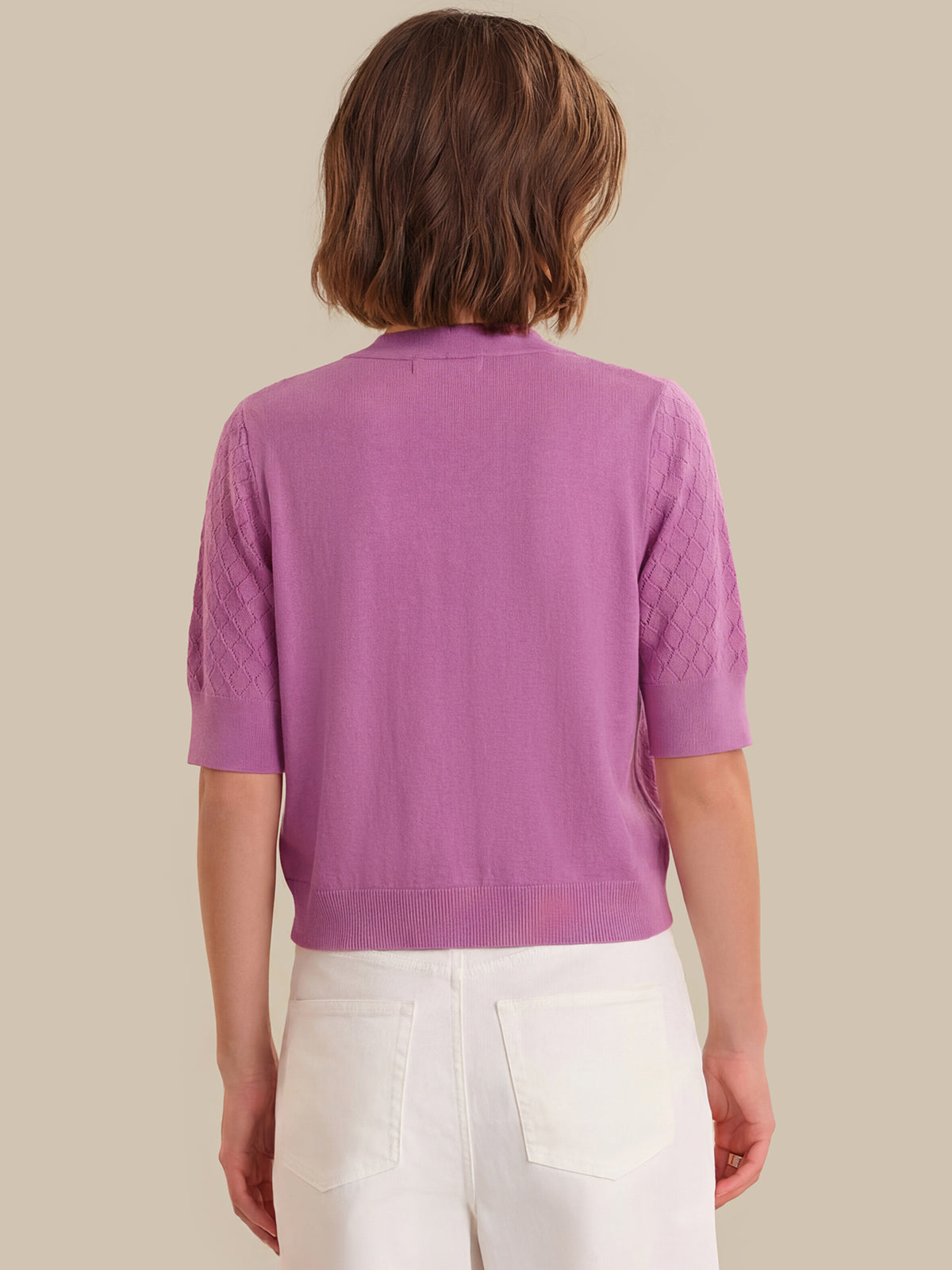 Person wearing a purple cardigan with a neutral background