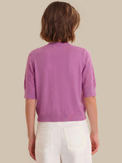 Person wearing a purple cardigan with a neutral background