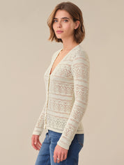 Woman wearing a cream lace cardigan against a beige background