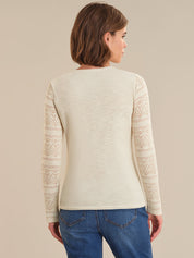 Woman wearing a cream sweater with lace details on a beige background