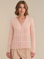 Woman wearing a pink lace cardigan against a beige background