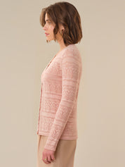 Woman wearing a pink lace cardigan against a beige background