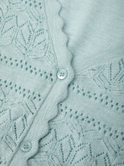 Close-up of a light blue knitted fabric with a button detail
