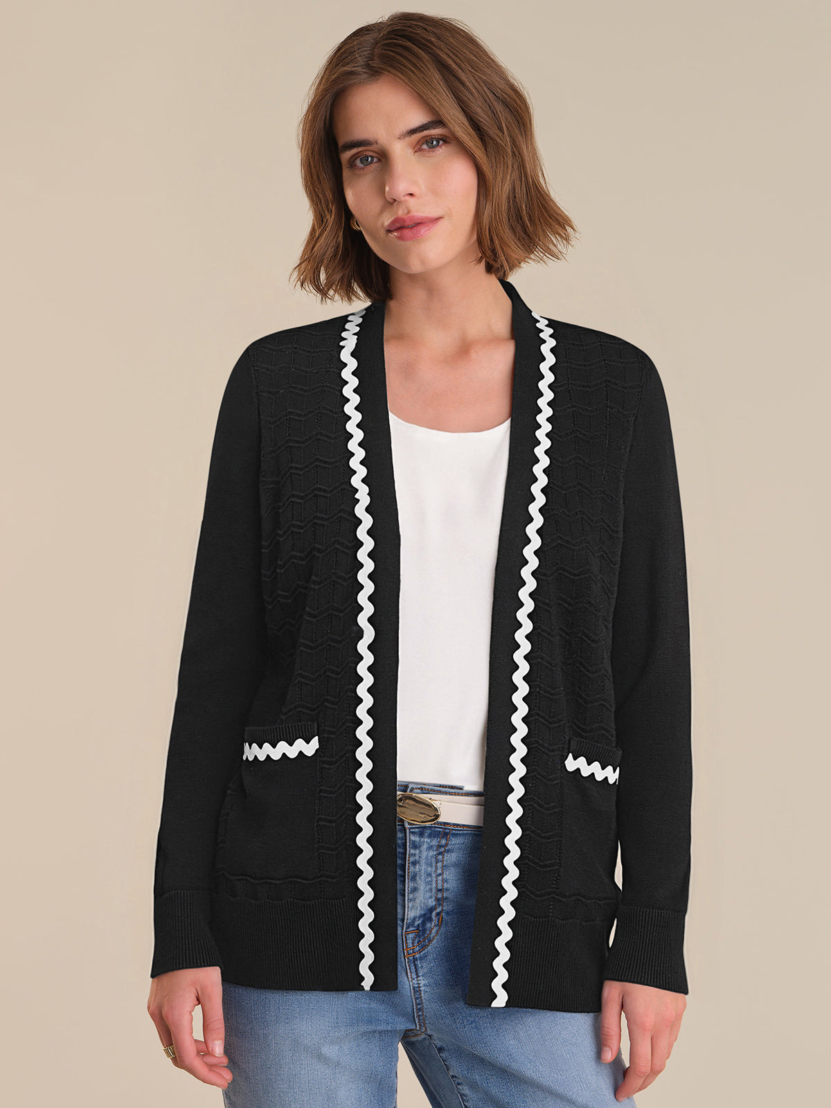 Woman wearing a black cardigan with white trim on a beige background