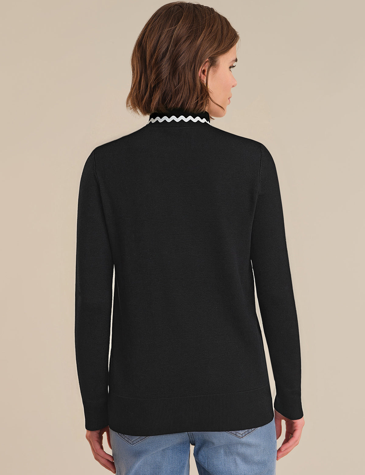 Person wearing a black long-sleeve top with a white collar against a beige background