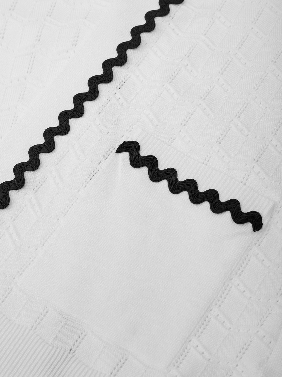 Close-up of black zigzag-patterned trim on a textured white fabric background