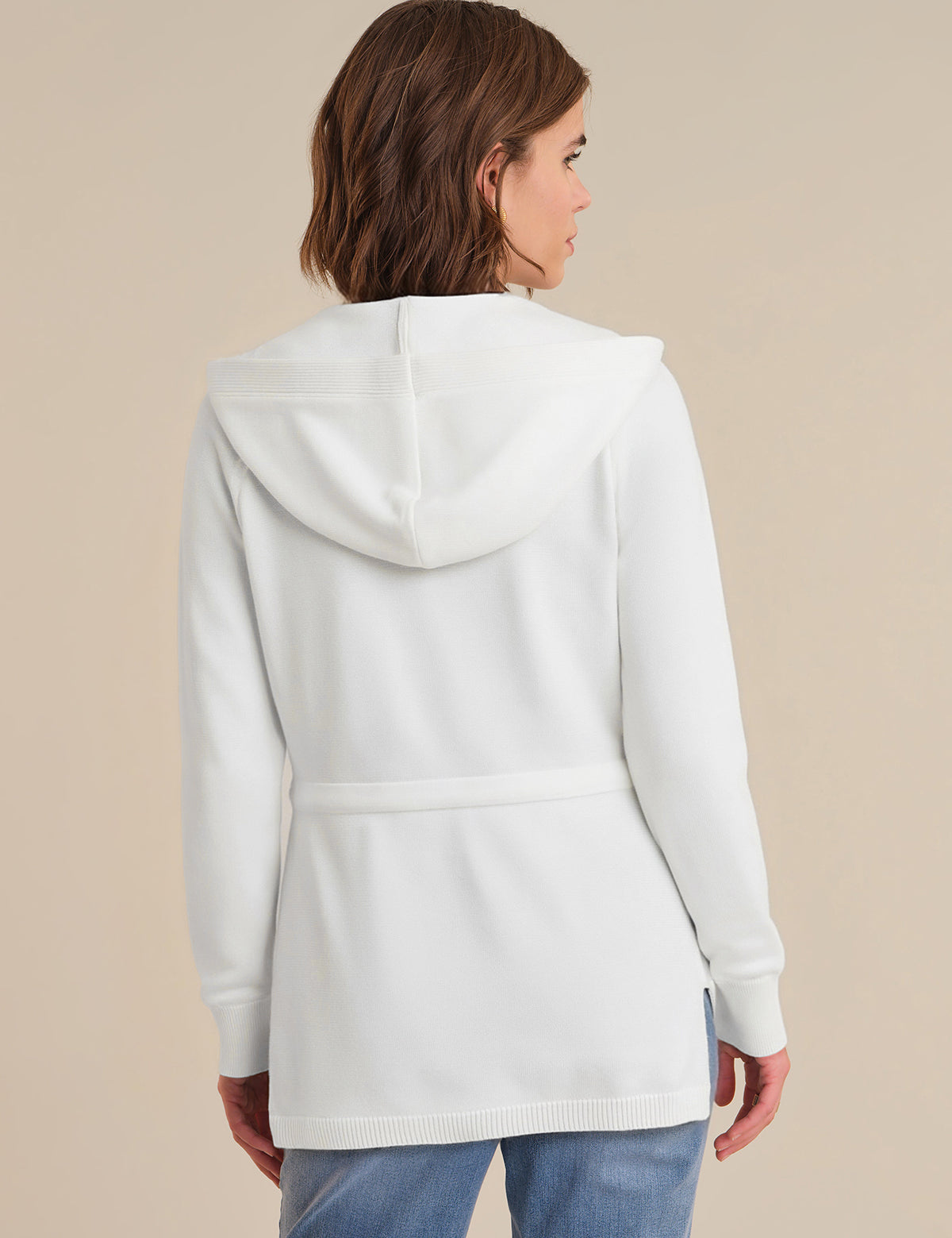 Person wearing a white hooded jacket on a beige background