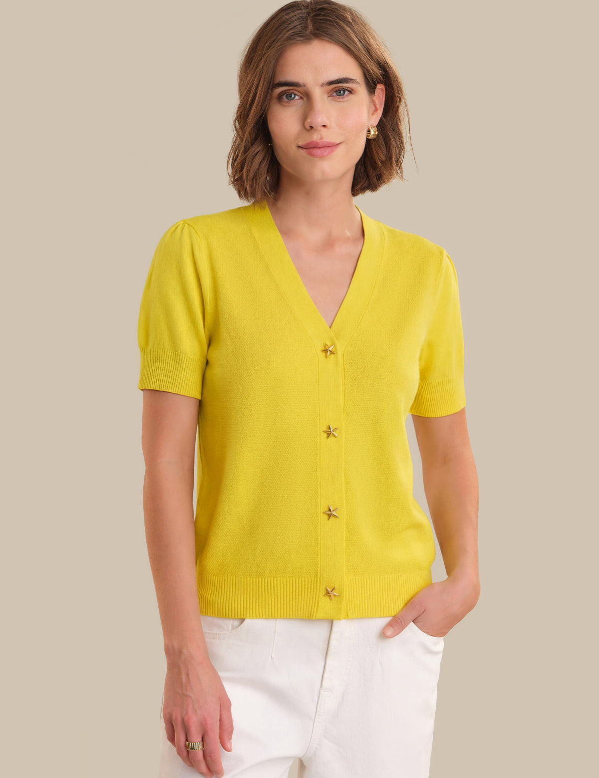 Woman wearing a yellow cardigan against a beige background