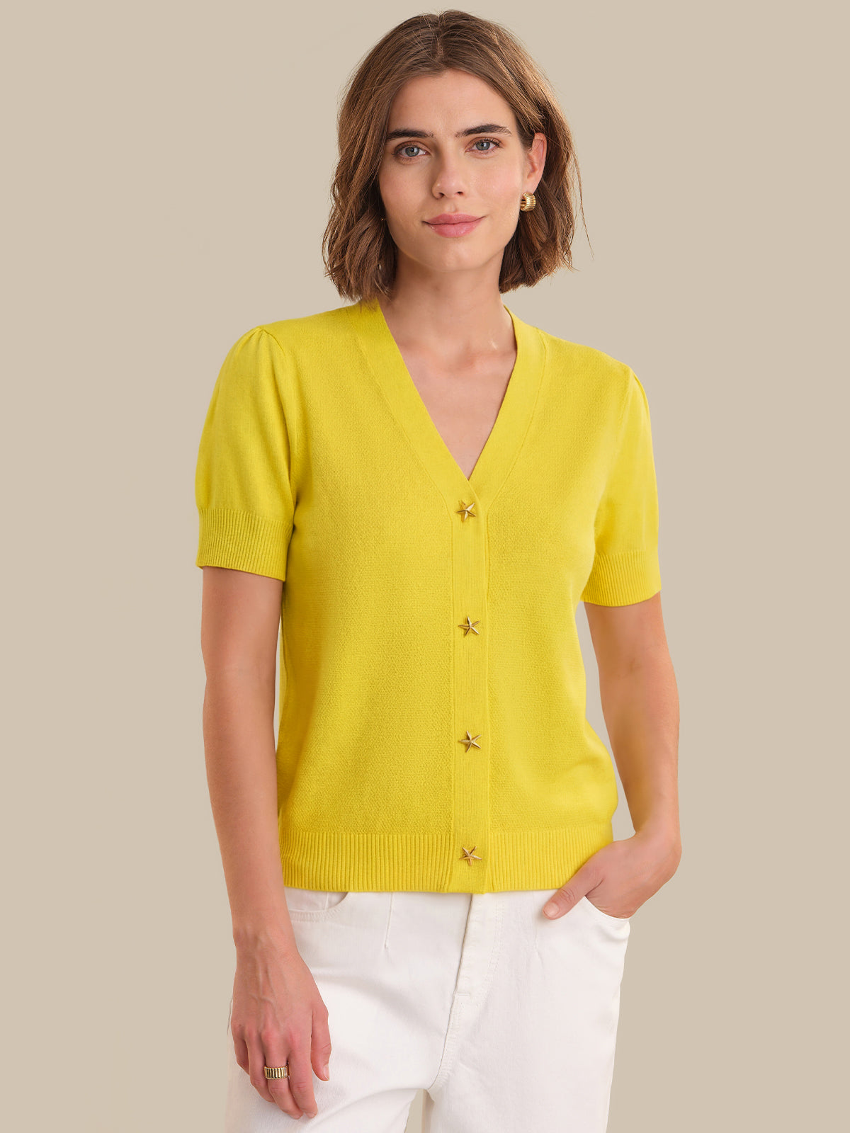 Woman wearing a yellow cardigan against a beige background