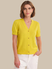 Woman wearing a yellow cardigan against a beige background