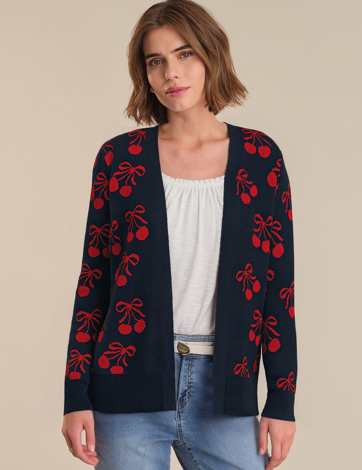 Woman wearing a navy cardigan with red cherry pattern on a beige background