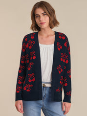 Woman wearing a navy cardigan with red cherry pattern on a beige background