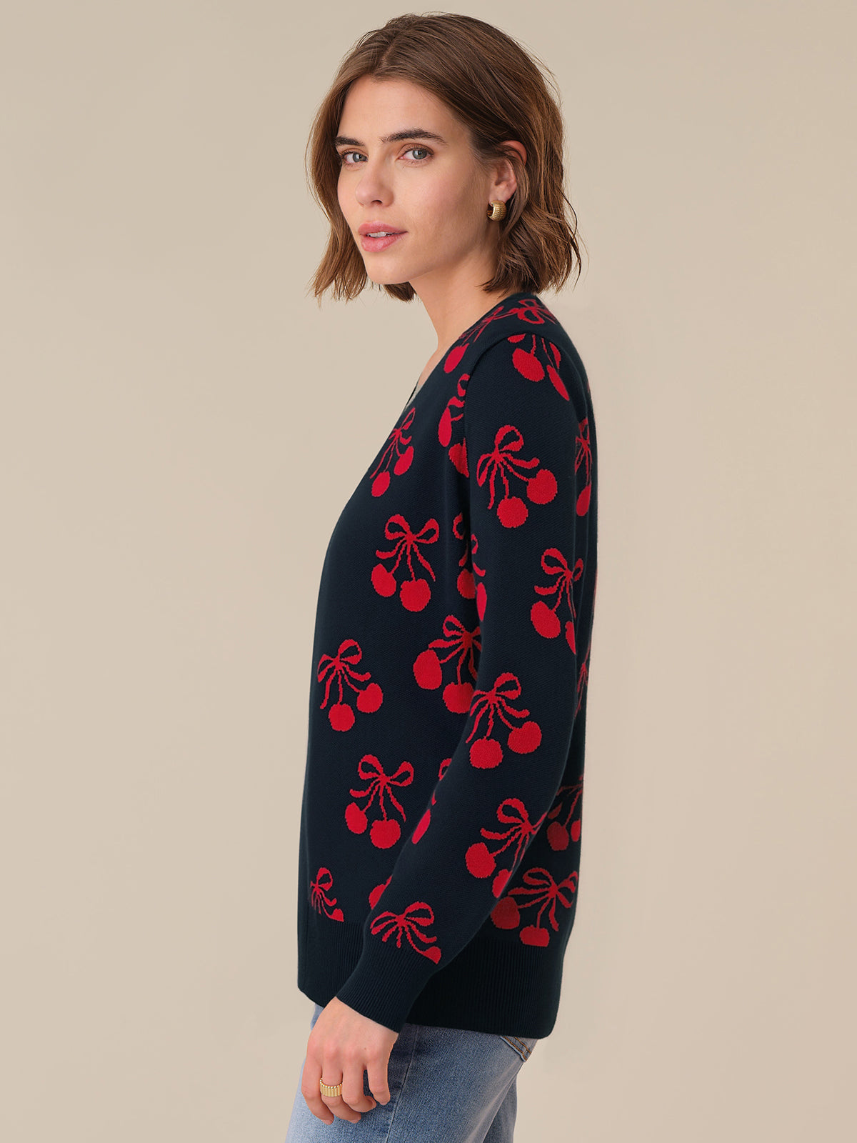 Woman wearing a navy cardigan with red cherry patterns on a beige background