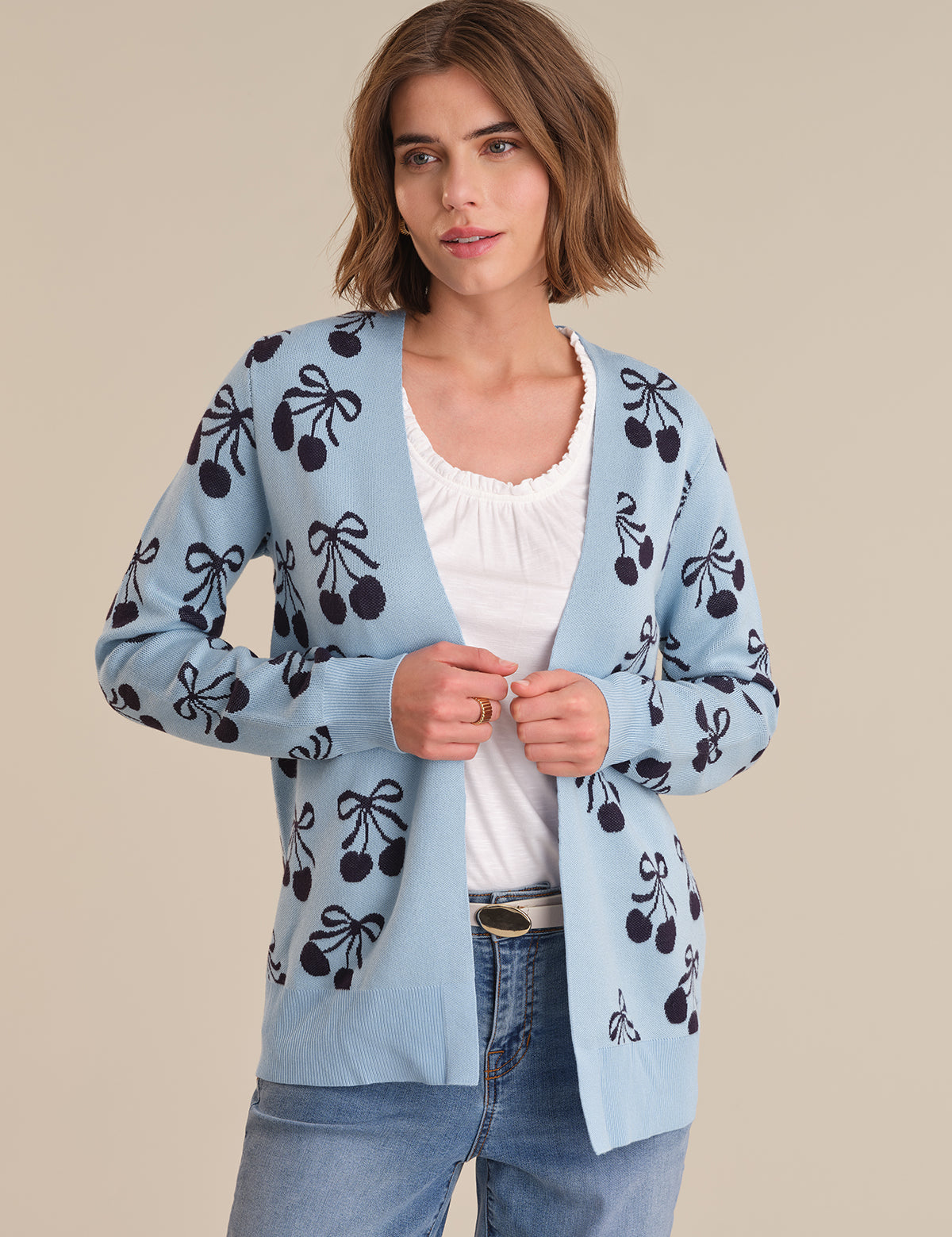 Woman wearing a light blue cardigan with black patterns on a beige background