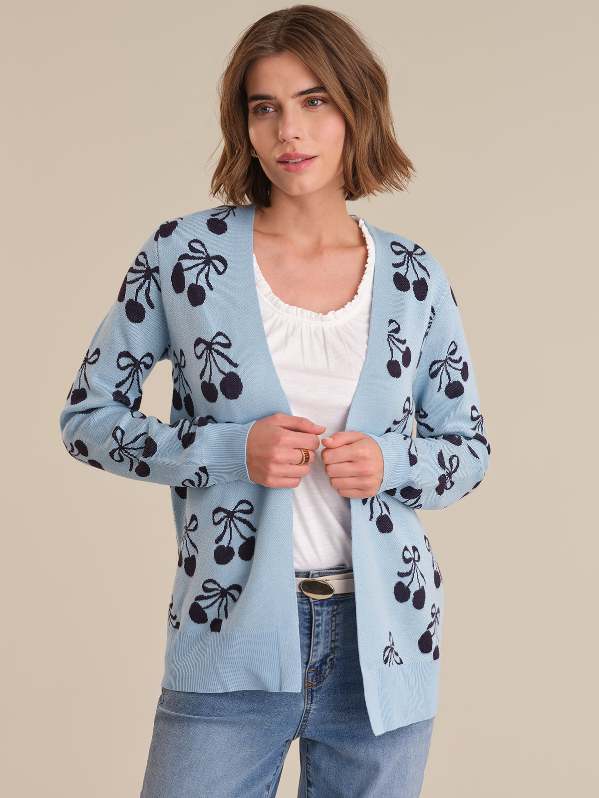 Woman wearing a light blue cardigan with black patterns on a beige background