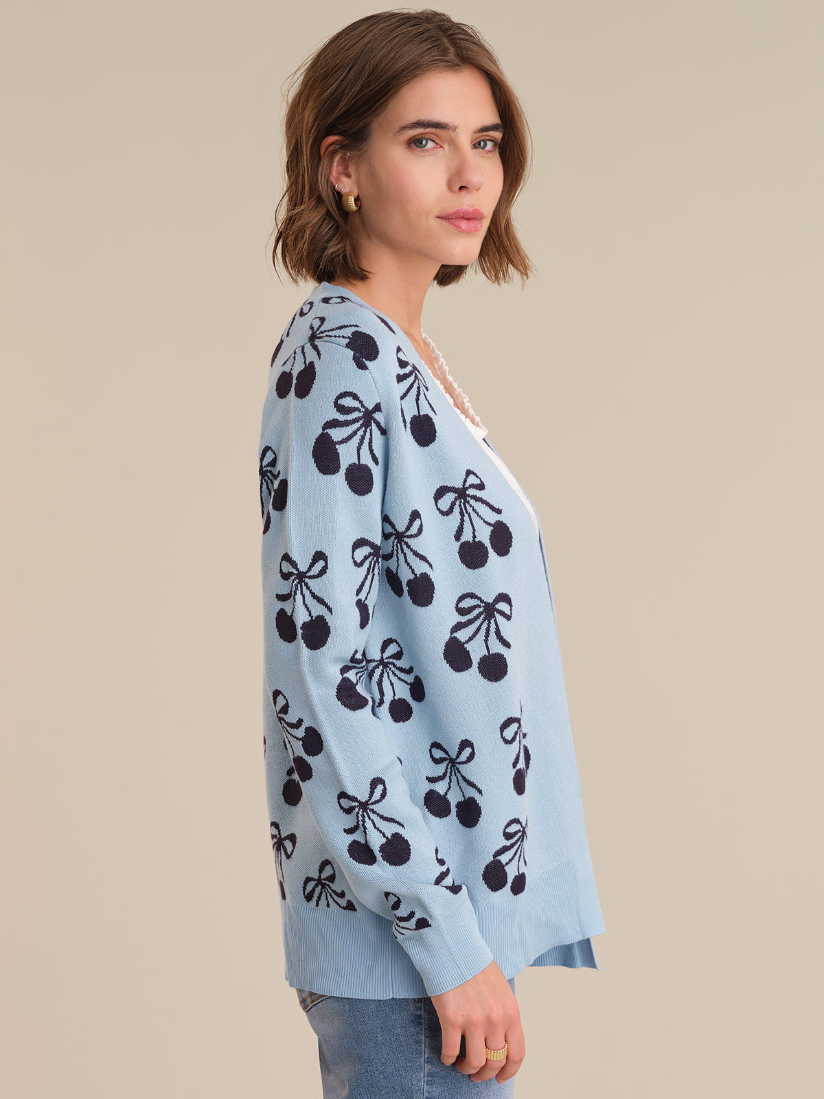 Woman wearing a light blue cardigan with black cherry pattern on a beige background