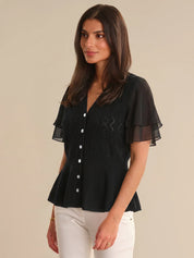 Woman wearing a black cardigan with sheer sleeves on a beige background