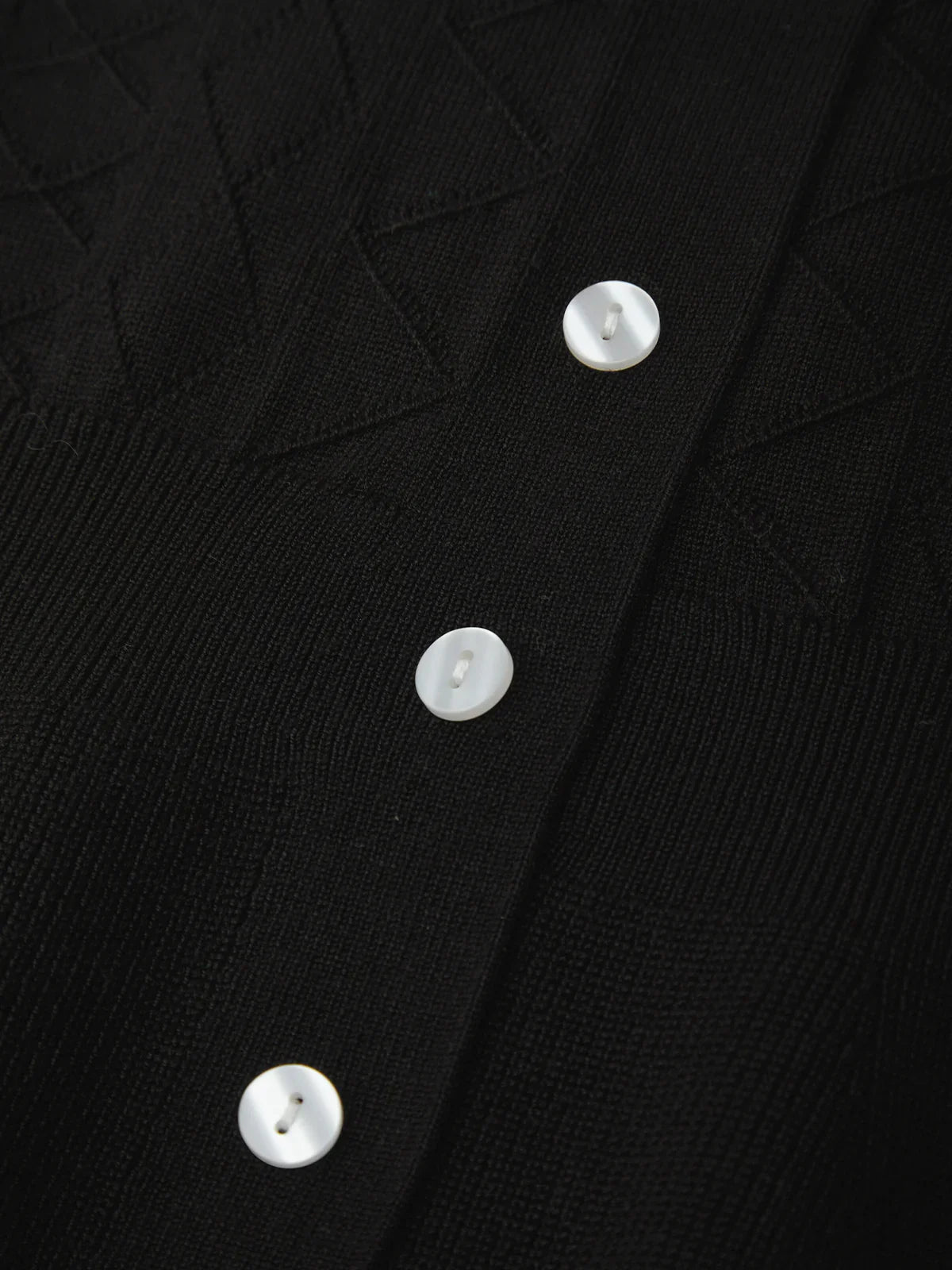 Close-up of a black garment with white buttons
