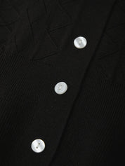 Close-up of a black garment with white buttons