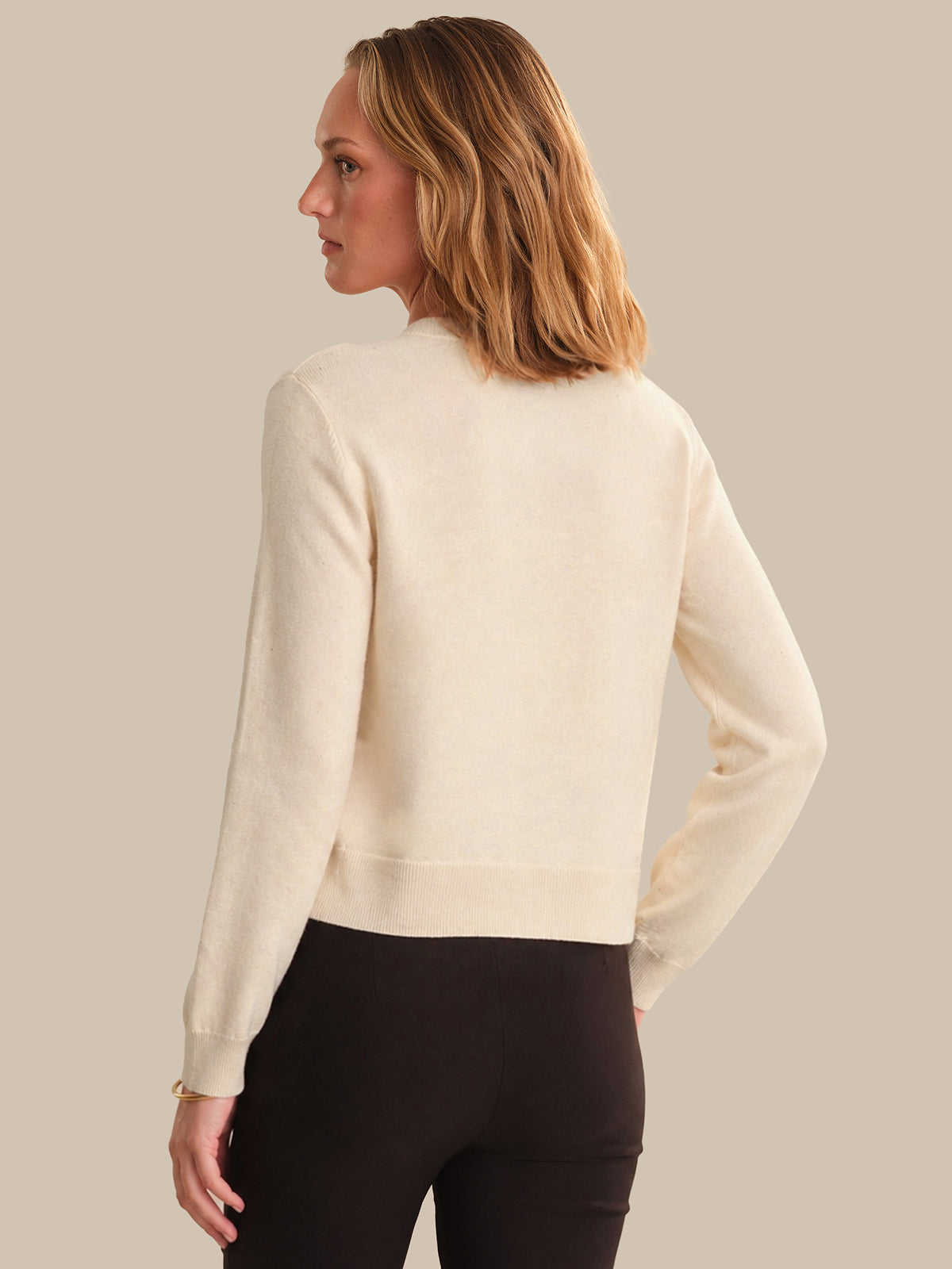 Woman wearing a beige sweater against a plain background